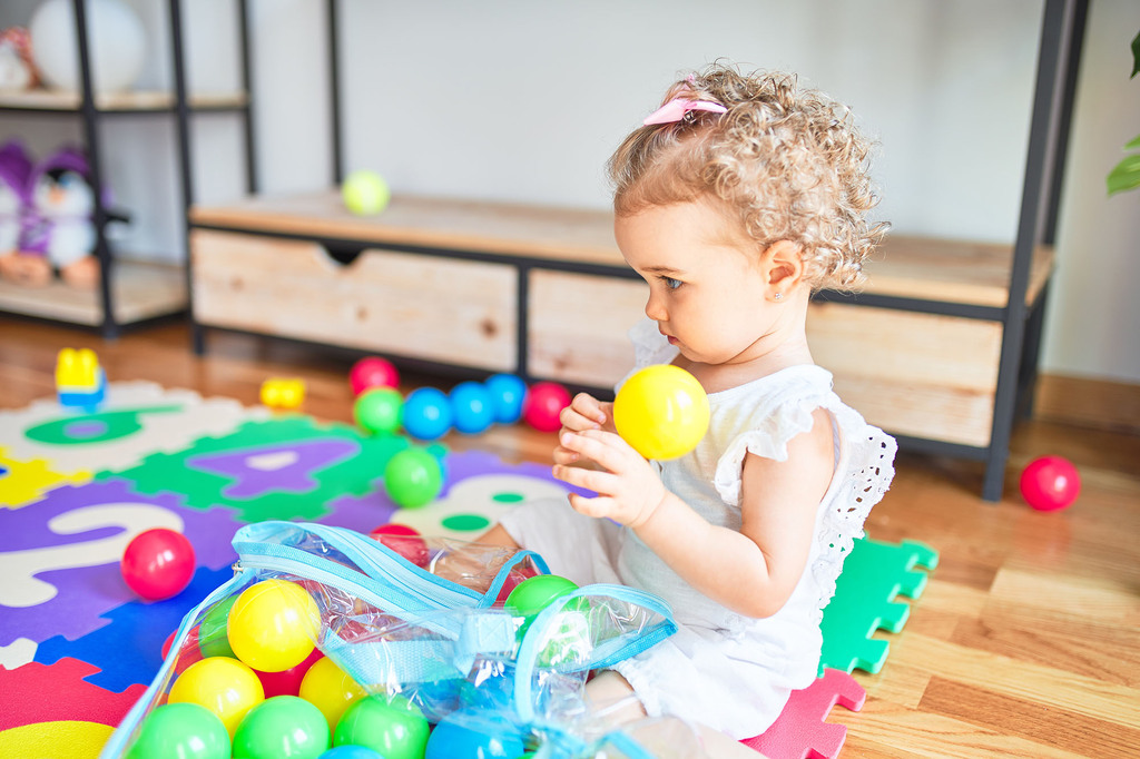 Kleines Mädchen spielt mit bunten Bällen