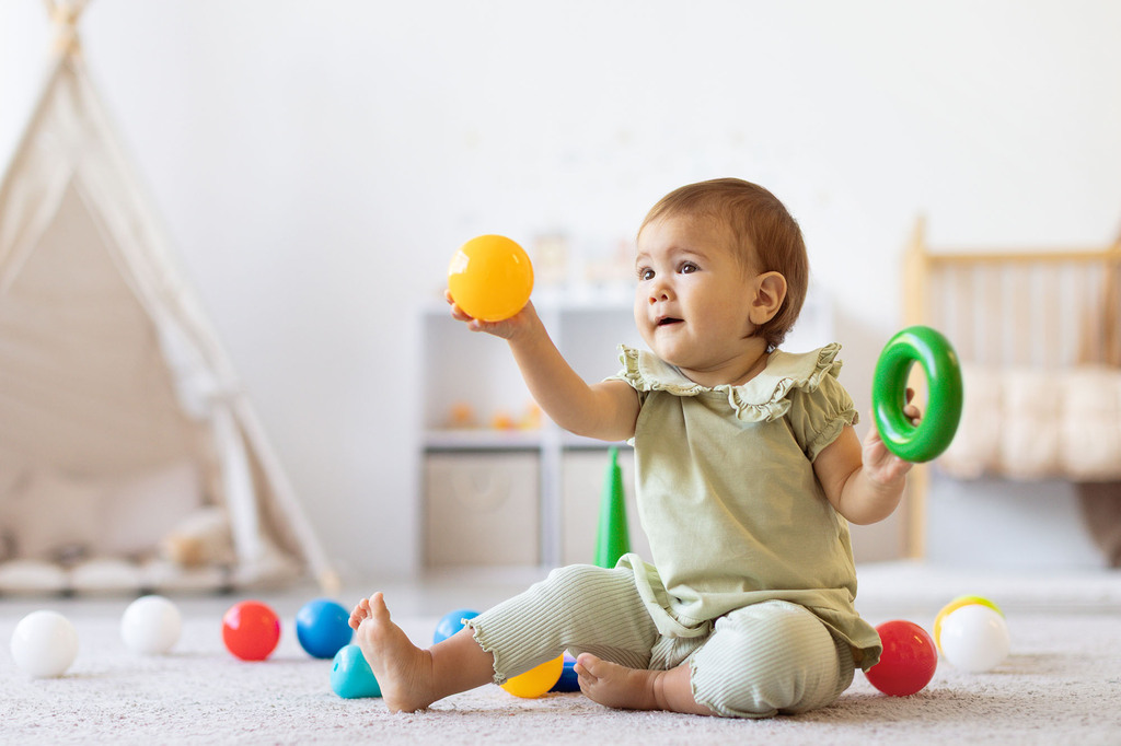 Kleines Mädchen spielt mit Bällen und Reifen