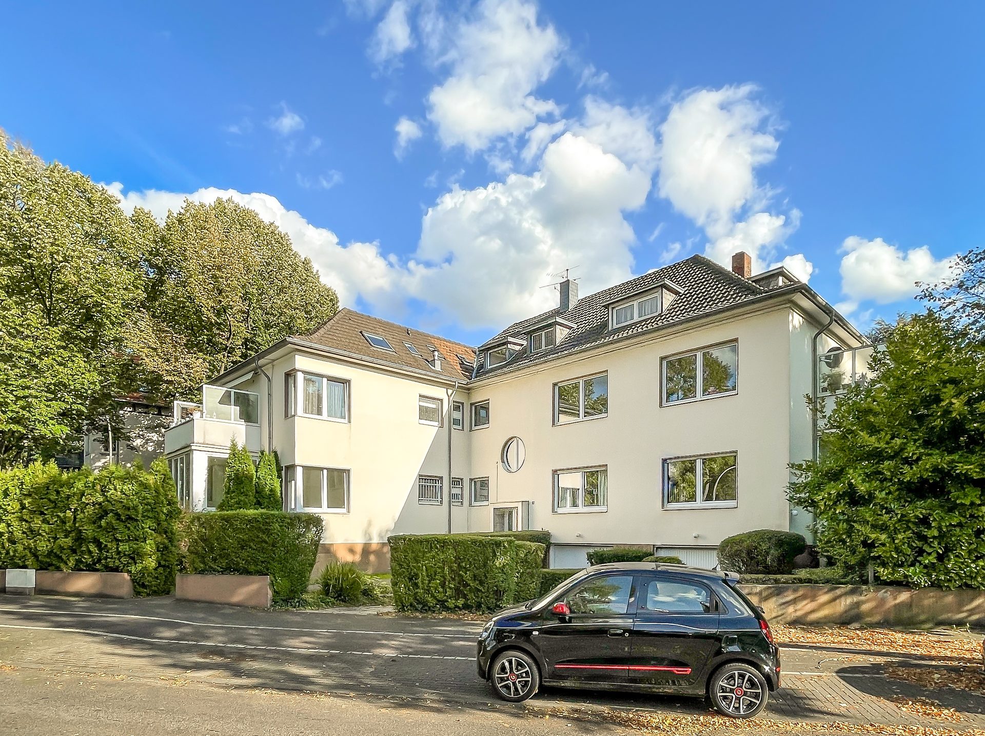 Drohnenaufnahme eines modernen Fachmarktzentrums mit großem Parkplatz und viel Grünflächen