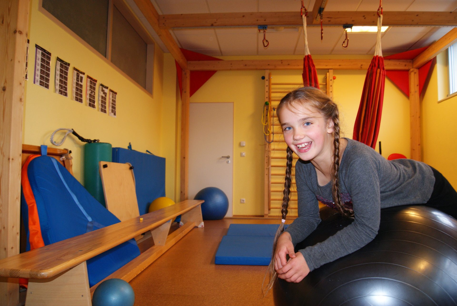 Ein Mädchen auf einem Medizinball während der Ergotherapie